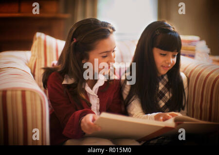 Zwei kleine Mädchen werden gesehen, um ein Buch zu lesen. Stockfoto