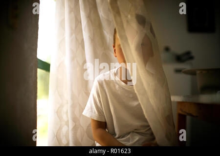 Anzeigen eines kleinen Jungen, der sich hinter einem Vorhang. Stockfoto