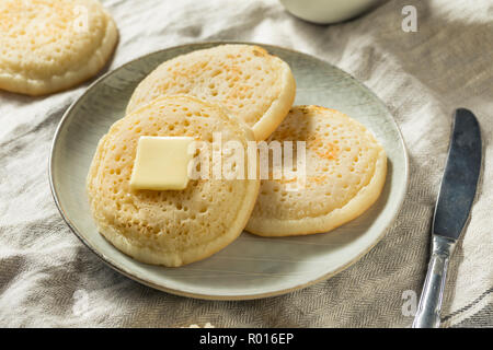 Hausgemachte Gegrillte britischen Crumpets mit Butter zum Frühstück Stockfoto