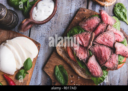Steak Sandwich, in Scheiben Roastbeef, Käse, Spinat, Tomaten, weiße Soße Stockfoto