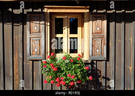Alte, traditionelle Fenster mit roter Blume Stockfoto
