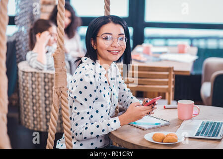 Nette Frau am Tisch sitzen begeistert Stockfoto