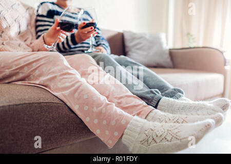 Zwei Freundinnen, Wein trinken und auf der Couch zu Hause sitzen. Frauen sprechen und entspannend. Klatsch Zeit Stockfoto