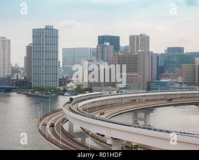 Moderne Autobahn mit Pkw und Bahn führt zu einer Brücke. Rainbow Bridge, Tokio, Japan. Stockfoto