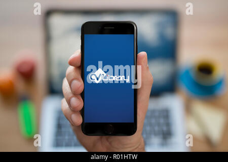 Ein Mann schaut auf seinem iPhone die zeigt die CV Bibliothek logo, während saß an seinem Computer Schreibtisch (nur redaktionelle Nutzung). Stockfoto