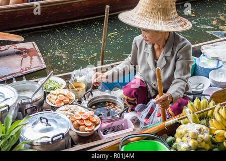 Damnoen Saduak, Thailand - 8. Oktober 2018: Frau Anbieter die Zubereitung von Speisen auf dem schwimmenden Markt. Der Markt ist ein sehr populär Reiseziel. Stockfoto