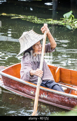 Damnoen Saduak, Thailand - 8. Oktober 2018: eine Frau Paddel ihr Boot am Kanal entlang. Der schwimmende Markt hier ist ein sehr beliebtes Touristenziel. Stockfoto