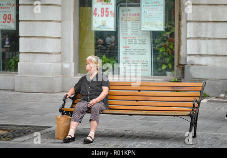 WUHAN, China - September 08, 2018: Alte asiatische Frau sitzt auf den alten Stuhl in den Park. Sie sehen aus wie warten auf jemanden. Stockfoto