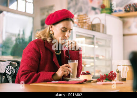 Französische Frau das Tragen der roten Outfit trinken Latte in Nizza Bäckerei sitzen Stockfoto