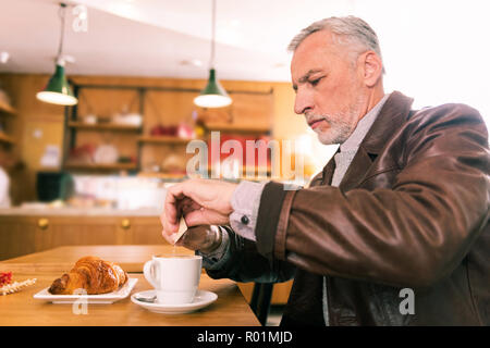 Grauhaarige Geschäftsmann Ausgaben morgen in Französische Bäckerei Stockfoto