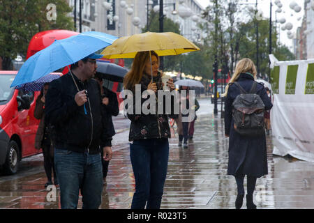 Die Oxford Street, London, UK. 1 Nov, 2018. Kunden Schutz vor dem Regen unter Sonnenschirmen Regen in London fällt. Credit: Dinendra Haria/Alamy leben Nachrichten Stockfoto