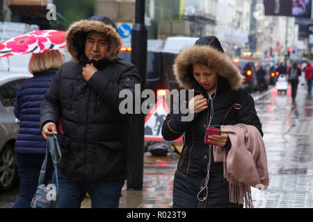 Die Oxford Street, London, UK. 1 Nov, 2018. Kunden Schutz vor dem Regen unter Sonnenschirmen Regen in London fällt. Credit: Dinendra Haria/Alamy leben Nachrichten Stockfoto