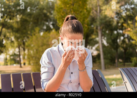 Junge Frau Niesen im Freien, während Sie eine Allergie Stockfoto