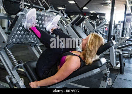 Junge passende Frau an der Turnhalle tun Bein Muskel Übung mit Beinpresse Maschine. Weibliche Athleten bei einem Fitnessraum, Arbeiten mit gewichteten Bein Training m Stockfoto