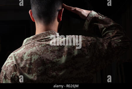 US-Armee. Junge Soldat salutierte stehend auf schwarzem Hintergrund Stockfoto