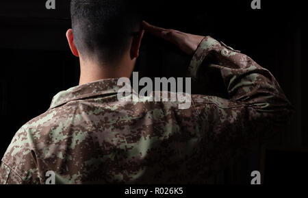 US-Armee. Junge Soldat salutierte stehend auf schwarzem Hintergrund Stockfoto