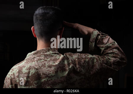 US-Armee. Junge Soldat salutierte stehend auf schwarzem Hintergrund Stockfoto