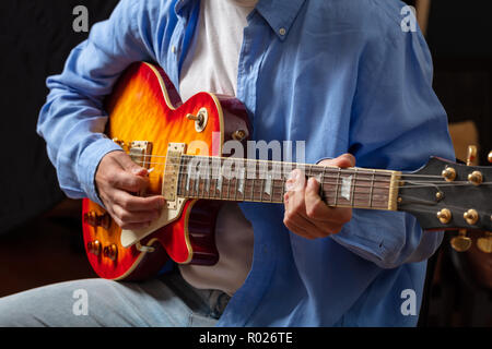 Junge Mann spielt E-Gitarre, bis Ansicht schließen, dunklen Hintergrund Stockfoto