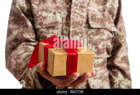 Weihnachten und Armee. Junge Soldat Holding ein Weihnachtsgeschenk auf weißem Hintergrund Stockfoto