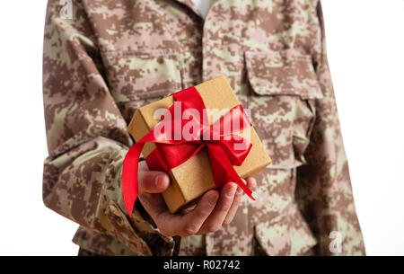 Weihnachten und Armee. Junge Soldat Holding ein Weihnachtsgeschenk auf weißem Hintergrund Stockfoto