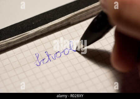 Die menschliche Hand schreiben Schule auf Notepad mit Tinte, Kugelschreiber Stockfoto
