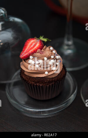 Schoko Cupcakes mit Erdbeeren auf einem Standfuß aus Glas. Stockfoto
