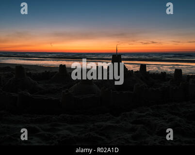 Silhouette einer Sandburg an der Wasserlinie nach Sonnenuntergang Stockfoto