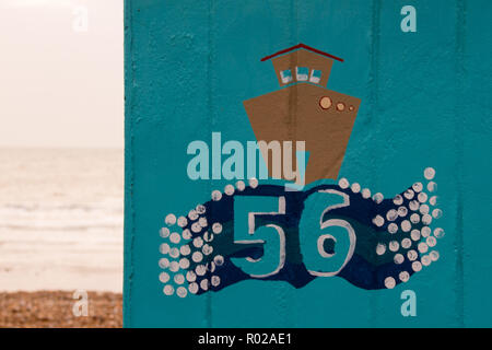 Braun Boot auf auf einem blauen Englisch Beach Hut mit der Zahl 56 und den Strand und das Meer im Hintergrund Stockfoto