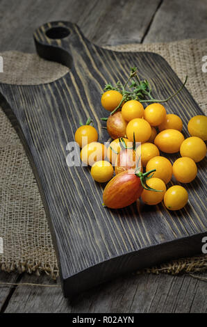 Gelbe und rote Kirschtomaten auf Holz Schneidebrett. Close Up. Stockfoto