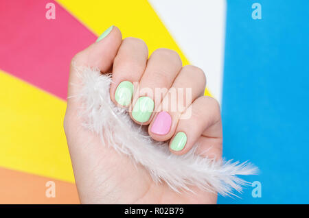 Schöne weibliche Hand mit hellgrün und rosa Nail Design auf farbigen Hintergrund. Stockfoto