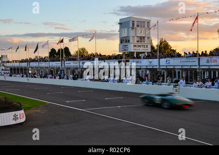 Vintage-Motorrennen bei Sonnenuntergang am Abend im Goodwood Revival. Ausdauerrennen. Rennwagen auf Zielgerade, Boxengeraden Stockfoto