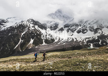 Zwei Touristen wandern auf den Gipfel des Cheget in Russland montieren. Snowy und nebliger Landschaft um, Blick auf Gletscher Semerka Stockfoto