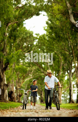 Im mittleren Alter Mann mit seinem Sohn, wie sie ihr Fahrrad schieben. Stockfoto