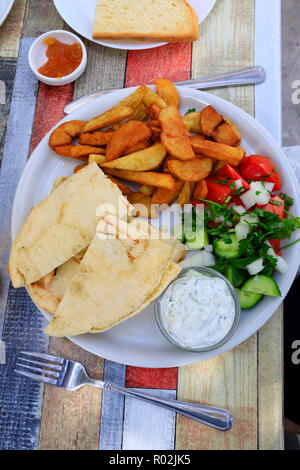 Zyprischen Essen auf einem weißen Teller in einem Village Taverna. Halloumi in Pitta Brot, Pommes, Salat und Tzatziki, mit einem seitlichen Auftrag von Toast und Marmelade. Zypern Ülg Stockfoto