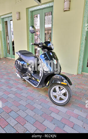 Schwarz Vespa Roller auf dem Bürgersteig geparkt neben einem Unternehmen in Seaside in Florida, USA. Stockfoto