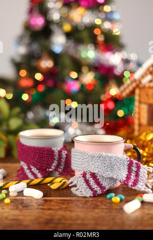 Tassen in der gemütlichen Schals auf dem Hintergrund der Weihnachtsbäume. Das neue Jahr noch leben. Stockfoto