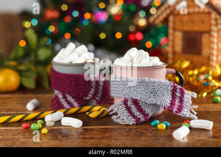 Cups mit Kakao und Marshmallow in der gemütlichen Schals auf dem Hintergrund der Weihnachtsbaum. Das neue Jahr noch leben. Stockfoto
