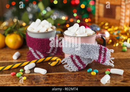 Zwei Tassen in der gemütlichen Schals mit einem heißen süsses Getränk und Marshmallows. Close-up. Stockfoto