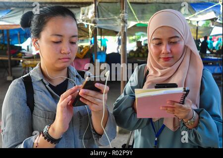 Kota Kinabalu in Sabah Malaysia - May 28, 2018: Zwei malaysische Teenager mit Smartphone auf Telipok Straße. Stockfoto