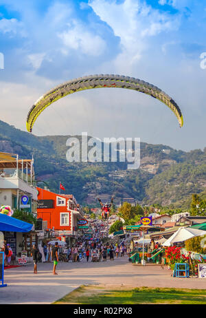 Fethiye, Marmaris/Türkei - 19. August 2018: Tandem Paraglider über Land und belebten Straße von Ölüdeniz im Hintergrund Stockfoto