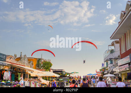 Fethiye, Marmaris/Türkei - 19. August 2018: Tandem Paraglider über Land und belebten Straße von Ölüdeniz im Hintergrund Stockfoto