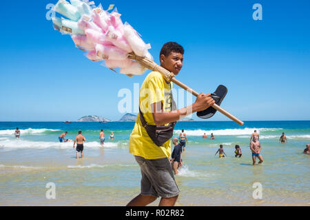 RIO DE JANEIRO - ca. Februar 2018: Eine junge brasilianische Hersteller Spaziergänge verkaufen Baumwolle Zuckerwatte entlang dem Ufer von Ipanema Beach. Stockfoto