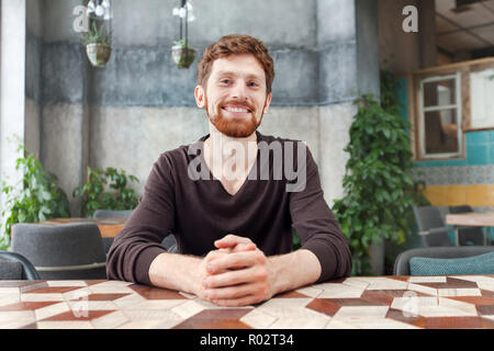 Lächelnd bärtiger Mann am Tisch im Cafe Stockfoto