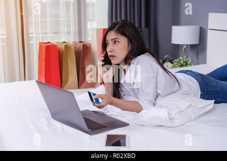 Frau auf dem Bett Einkaufen online mit Smartphone und Kreditkarte Stockfoto