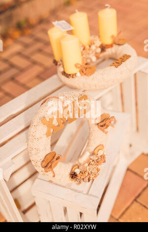 Weihnachten Home Dekoration mit brennenden Lichtern auf weißem Holz- Hintergrund. Weihnachten Kranz, Moody saisonale Hintergrund Stockfoto