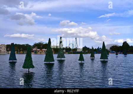 Orlando, Florida. Oktober 19, 2018 Weihnachtsbaum auf dem See, Achterbahn und bunten Läden an bewölkten Himmel in Seaworld Theme Park. Stockfoto