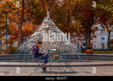 New York City, USA, Mai 2018, Frau sitzt an einem Tisch und macht eine Pause vor einem modernen Kunstwerk im Madison Square Park Stockfoto