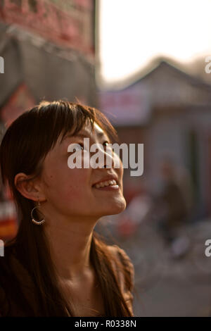 Lächelnde junge Frau auf der Suche nach oben. Stockfoto