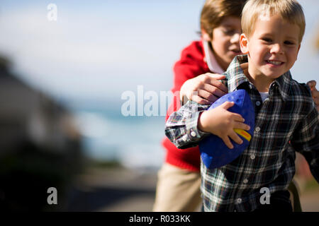 Zwei Jungen spielen mit einem Spielzeug Fußball außerhalb. Stockfoto