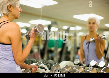 Reife Frau in einem Spiegel zu betrachten, während Sie im Fitnessstudio arbeiten. Stockfoto